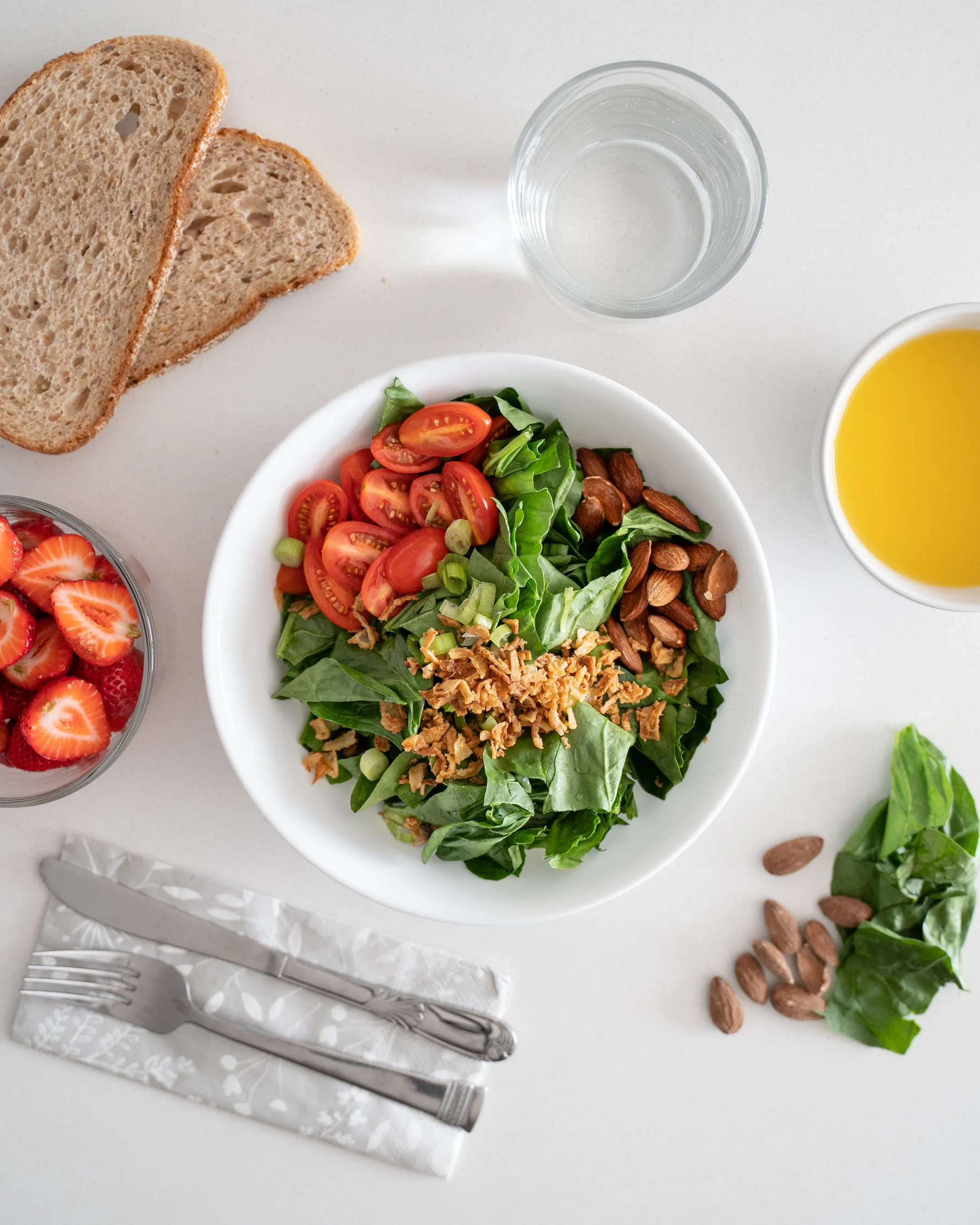 Vue du dessus : un bol de salade, des fraises, du pain complet et un verre d’eau